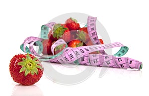 Diet scenery with measuring tape and fresh strawberries over white background