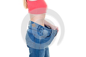 Diet slim woman shows her weight loss in wearing her old blue jeans profile side view