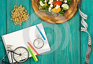 bicycle model, salad of fresh vegetables, red notepad, stopwatch