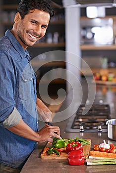 The diet starts today. a handsome young man chopping vegetables on the kitchen counter.