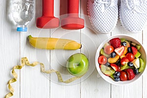 Diet and weight loss for healthy care with  fitness equipment, fresh water and fruit healthy, green apple, banana, cherry on white