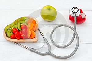 Diet and weight loss for healthy care with medical stethoscope, vegetable fruit and healthy food with red heart on the old white w