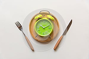 Diet and weight loss for healthy intermittent fasting lunchtime . Alarm clock and plate with cutlery on concrete background. photo