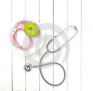 Diet and weight loss with measuring tap and green apple on wooden background top view