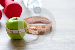 Diet and weight loss with measuring tap and green apple on wooden background top view.