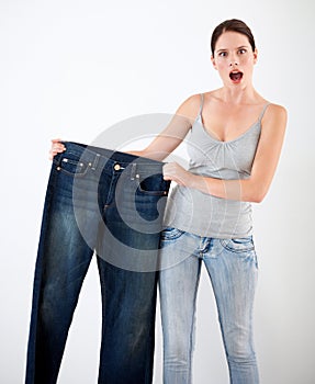 Diet, weight loss and woman with surprise from jeans, change in size or white background in studio. Shocked, portrait or
