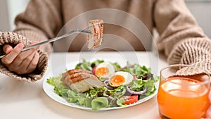 Diet woman eating a fresh healthy salad with grilled chicken breast at the table