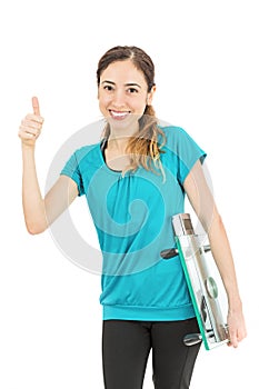 Diet woman giving thumbs up with a scale under her arm