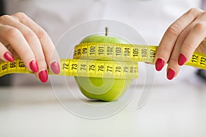 Diet. Woman holding a green apple and measuring