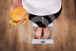 Diet. Woman Measuring Body Weight On Weighing Scale Holding Burg