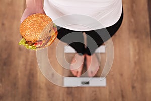 Diet. Woman Measuring Body Weight On Weighing Scale Holding Burger and apple. Sweets Are Unhealthy Junk Food. Dieting, Healthy Eat