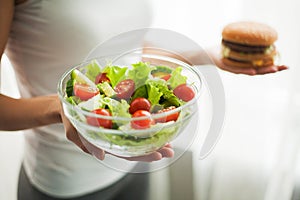 Diet. Woman Measuring Body Weight On Weighing Scale Holding Burger and Salat. Sweets Are Unhealthy Junk Food. Dieting