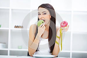 Diet. Woman Measuring Body Weight On Weighing Scale Holding Donut and apple. Sweets Are Unhealthy Junk Food. Dieting, Healthy Eat