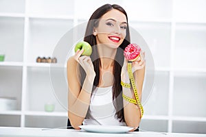 Diet. Woman Measuring Body Weight On Weighing Scale Holding Donut and apple. Sweets Are Unhealthy Junk Food. Dieting, Healthy Eat