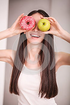 Diet. Woman Measuring Body Weight On Weighing Scale Holding Donut and apple. Sweets Are Unhealthy Junk Food. Dieting, Healthy Eat