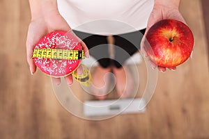 Diet. Woman Measuring Body Weight On Weighing Scale Holding Donut and apple. Sweets Are Unhealthy Junk Food. Dieting, Healthy Eati