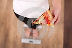 Diet. Woman Measuring Body Weight On Weighing Scale Holding Pizza. Sweets Are Unhealthy Junk Food. Dieting, Healthy Eating, Lifest