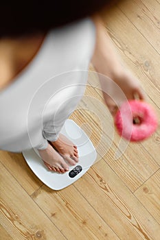 Diet. Woman On Weighing Scale, Holding Donut. Unhealthy Food. Ob