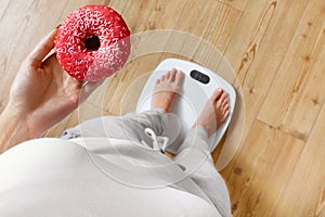 Diet. Woman On Weighing Scale, Holding Donut. Unhealthy Food. Ob