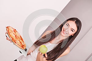Diet. Young beautiful woman makes a choice between healthy lifestyle and harmful food. The concept of healthy eating and obesity.