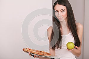 Diet. Young beautiful woman makes a choice between healthy lifestyle and harmful food. The concept of healthy eating and obesity.