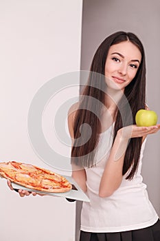 Diet. Young beautiful woman makes a choice between healthy lifestyle and harmful food. The concept of healthy eating and obesity.