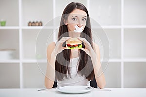 Diet. Young woman with duct tape over her mouth, preventing her