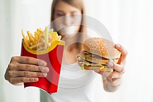 Diet. Young woman with duct tape over her mouth, preventing her to eat junk food. Healthy eating concept