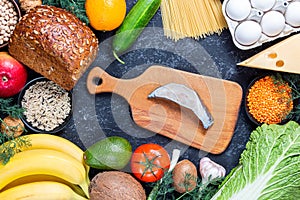 Dietary balance picture with fish steak, fruits, vegetables and seeds on black stone background