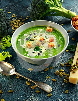 Dietary Broccoli smooth cream soup with sprinkle of sunflower seeds, parsley leaves and croutons on stone table.