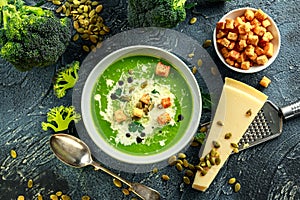 Dietary Broccoli smooth cream soup with sprinkle of sunflower seeds, parsley leaves and croutons on stone table.