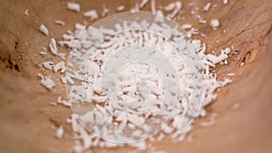 Dietary grated coconut flake ingredient in a wooden bowl