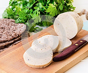 Dietary homemade boiled sausage mortadella from chicken breast with spices on a wooden cutting board.