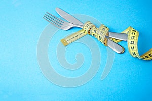 Dietary recipe dishes for breakfast, lunch or dinner. Fork and knife are wrapped in yellow measuring tape on blue background