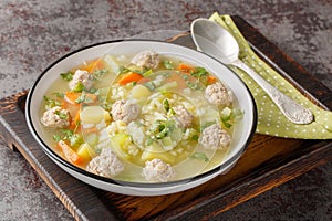 Dietary Rice meatball soup with celery, carrots, onions, potatoes and herbs close-up in a bowl. Horizontal