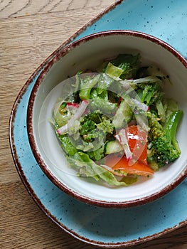 Dietary salad of fresh vegetables: cucumbers, radishes, tomatoes and broccoli, seasoned with olive oil.