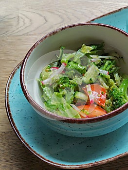 Dietary salad of fresh vegetables: cucumbers, radishes, tomatoes and broccoli, seasoned with olive oil.