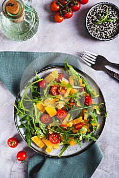 Dietary salad of orange slices, cherry tomatoes and arugula on a plate top and vertical view