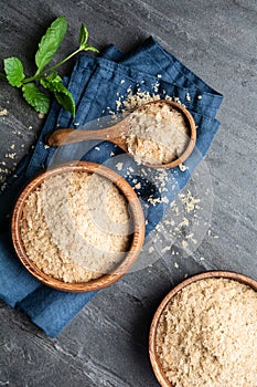 Dietary supplement, unfortified nutritional yeast flakes in a wooden bowl and scoop