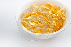 Dietary supplementation. Capsules of fish oil in the white bowl, light background