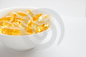 Dietary supplementation. Capsules of fish oil in the white bowl, light background