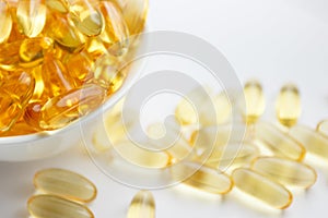 Dietary supplementation. Capsules of fish oil in the white bowl, light background