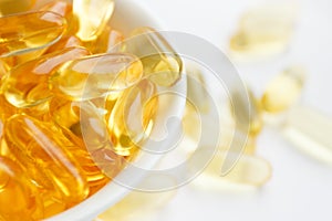 Dietary supplementation. Capsules of fish oil in the white bowl, light background