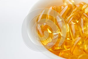 Dietary supplementation. Capsules of fish oil in the white bowl, light background