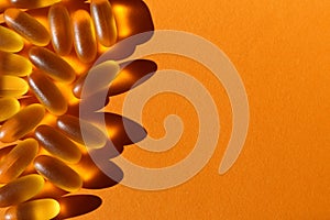 Dietary supplementation. omega-3 fish fat oil capsules. Orange background