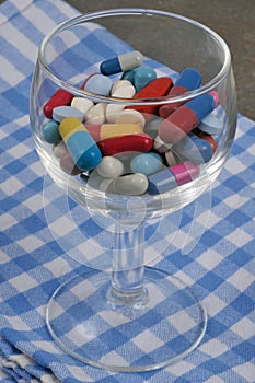 Dietary supplements in a wine glass on a checkered napkin