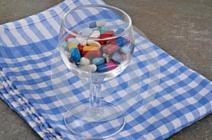 Dietary supplements in a wine glass on a checkered napkin