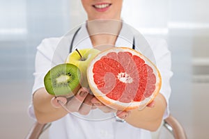 Dietician holding fresh sliced fruits photo