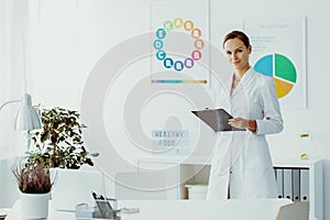 Dietician with notes and standing in her office photo