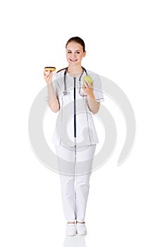 Dietician holding sweet doughnut and fresh healthy green apple.